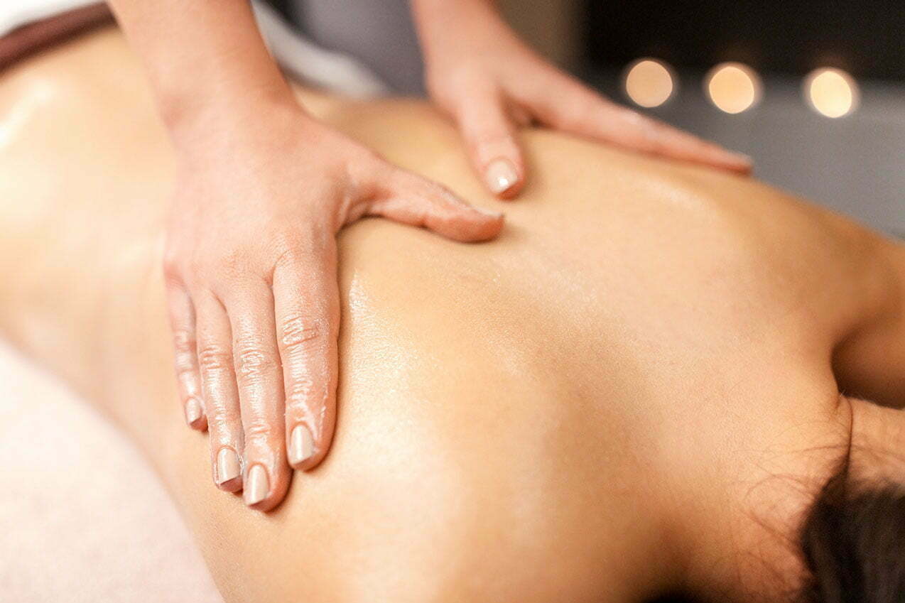 woman lying and having back massage at spa